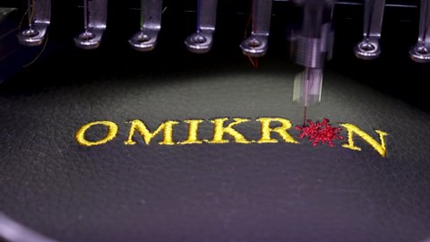 Machine embroidery with the inscription Omicron on black leather with yellow thread. Caption design and virus form, close up 4k video.