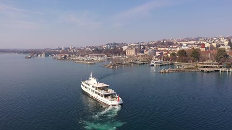 Lausanne, Switzerland - March 03 2022: Aerial drone footage the Henry-Dunant CGN cruise boat that leaves the Ouchy harbor in Lausanne city on the lake Geneva in Switzerland, with a rotation motion