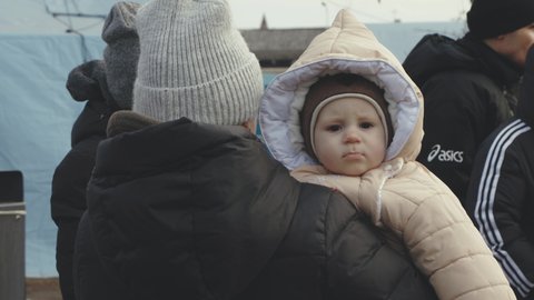 Lviv, Ukraine - March 15, 2022: Woman holding her child at the hands. Ukrainian mother and son refugees on Lviv railway station waiting for train to escape to Europe