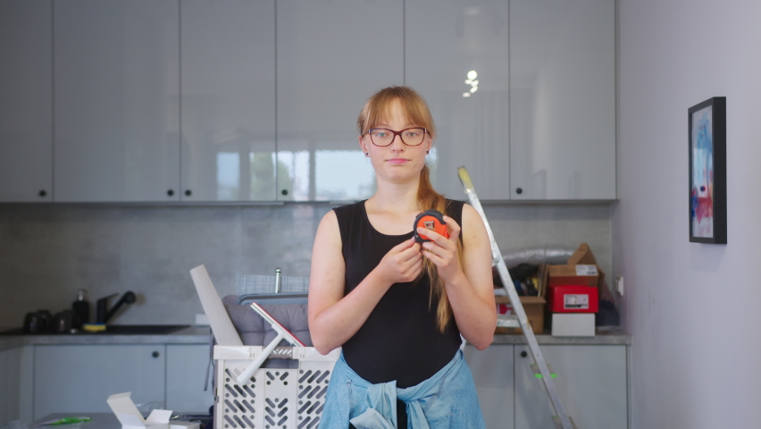 Inexperienced young woman holding a measuring tape during a home renovation