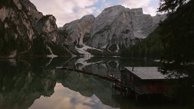 lago di braies static shot iconic boat house and boats in line mountain reflection in high mountain Italian dolomites lake that many people dream of traveling to and experience.