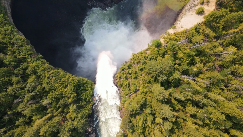 Helmcken Falls cascading over a cliff into the Murtle River with a small rainbow below in British Columbia, Canada. Aerial top down view