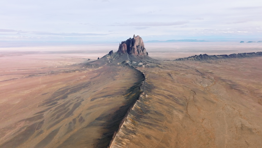Giant Shiprock formation in the middle of the flat terrain with stones along sandy soil as seen from above. Drone footage of beautiful natural environment with dry climate. High quality 4k footage