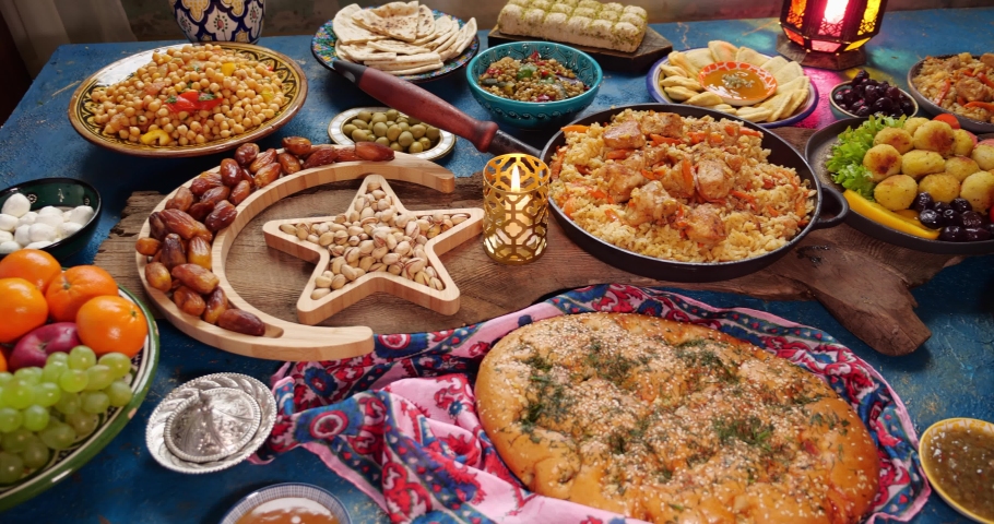 Traditional Dishes to Serve During Ramadan - Falafel, samosa, chickpeas, beans, pita bread, pilaf, tajine, couscous, dates, olives. A set table for the celebration of Eid al-Fitr. Family dinner Royalty-Free Stock Footage #1088112687