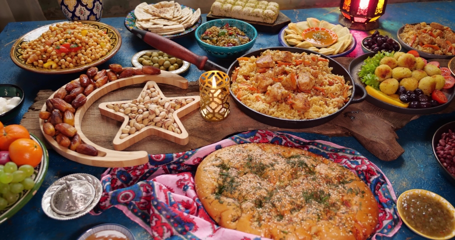 Traditional Dishes to Serve During Ramadan - Falafel, samosa, chickpeas, beans, pita bread, pilaf, tajine, couscous, dates, olives. A set table for the celebration of Eid al-Fitr. Family dinner | Shutterstock HD Video #1088112687
