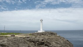 YOMITANSON, OKINAWA, JAPAN - AUGUST 2021 : View of lighthouse at Zanpa Misaki (Cape Zanpa) and East China Sea (Ocean) in daytime. Summer holiday, vacation and resort concept video.