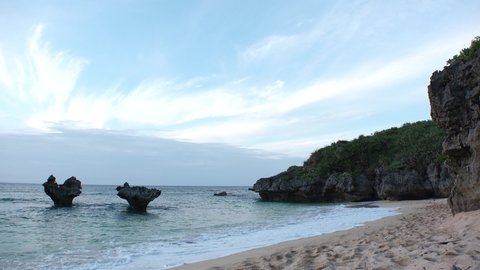 KOURI ISLAND, NAKIJIN, OKINAWA, JAPAN - AUG 2021 : View of Thinu-hama beach (Ocean or sea) and heart rock in sunset time. Summer holiday, vacation and resort concept video.