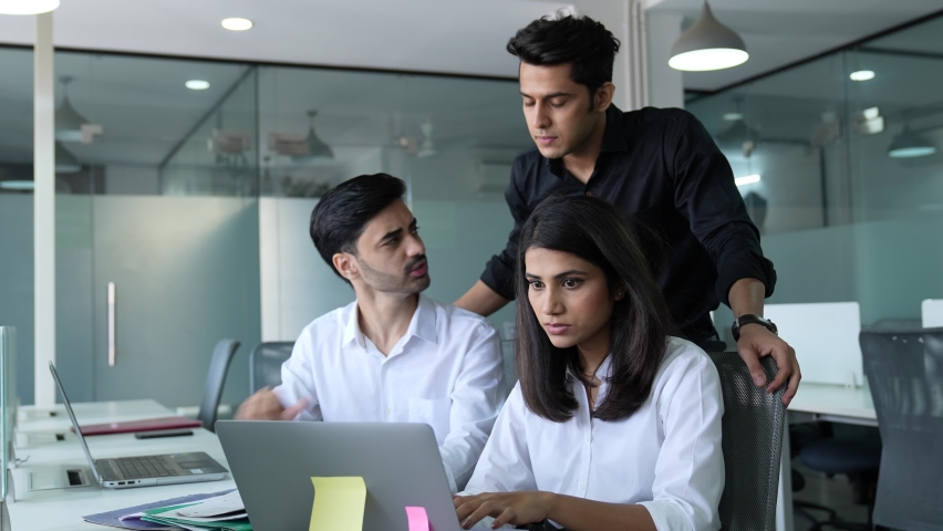 Young Indian team of business partners are discussing an upcoming project using a laptop and paper. Asian group of male and female corporate office employees are interacting inside office. Royalty-Free Stock Footage #1088116251