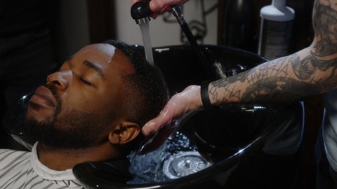 Barber washes his hair and gives a massage to a client of a hairdresser - close up