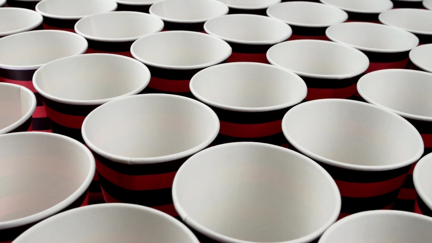 Row red and black disposable paper cup for coffee or hot beverage on dark backdrop rotate slowly.