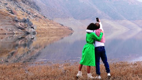 Lovely Happy Couple taking Selfie photo while enjoying mountains lake and nature of hills.