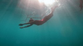 Woman diving underwater in pristine clear water cenote in Mexico. Female swimming underwater in blue lagoon enjoying tropical vacations 