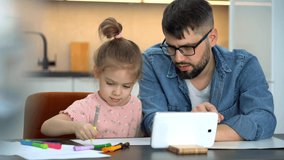 Father and little child learn to draw watching drawing lesson on on tablet on internet at home. Online education concept. Video tutorial, drawing training.