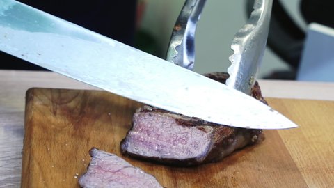 Slicing juicy ribeye meat steak.