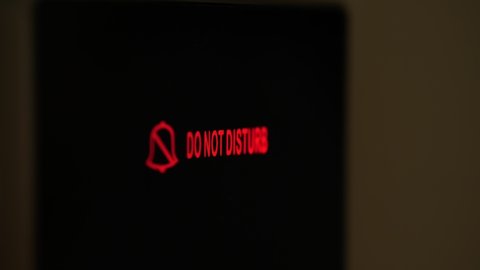 do not disturb. close-up. the sign is lit in red. electronic plate. a digital board with an inscription - do not disturb, in the hotel room. female finger presses the button.