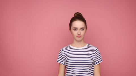 Portrait of woman showing dab dance move, famous internet gesture of triumph and success, performing dabbing trends, wearing striped T-shirt. Indoor studio shot isolated on pink background.