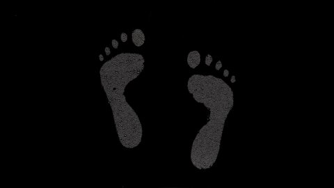 Inverted footprints printed on the wet glass blown off with air stream on black background | foot care concept