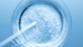 Top view macro shot of glycerin pouring into beaker with water creates ripples on its surface on pale blue background | Abstract body care cosmetics formulation concept - Powered by Shutterstock - Get 15% off with code: PIKWIZARD15