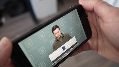 On a smart phone screen watching the president of Ukraine Volodymyr Zelenskyy giving a speech while his country is invaded by Russia. Watching the news online MONTREAL CANADA MARCH 2022