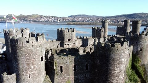 Flags flying on medieval Conwy castle Welsh market town battlements aerial view historical harbour