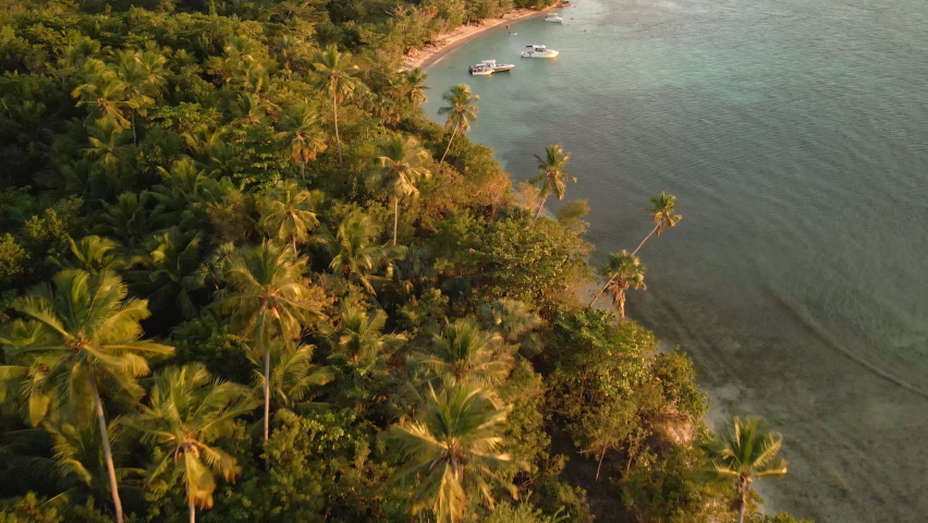 Flying drone on top of boats on the beach during sunset time