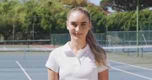 Video of happy caucasian female tennis player looking at camera. professional tennis training, sport and competition concept.
