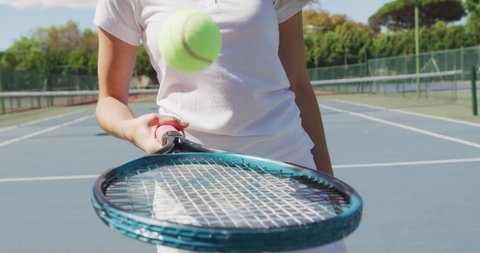 Video of midsection of caucasian female tennis player holding racket and bouncing ball. professional tennis training, sport and competition concept.