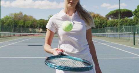 Video of midsection of caucasian female tennis player holding racket and bouncing ball. professional tennis training, sport and competition concept.