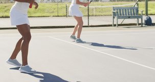 Video of happy diverse female tennis players exercising on court. professional tennis training, sport and competition concept.