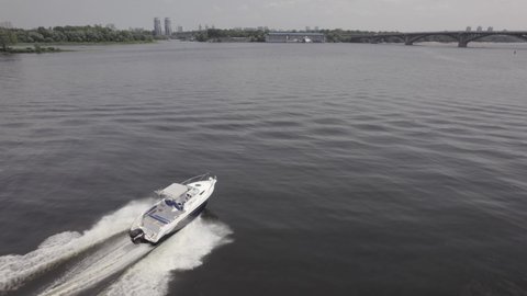 Aerial view of luxury white speed boat cruising in high speed in blue sea. . Beautiful and long waves left by a motor boat.