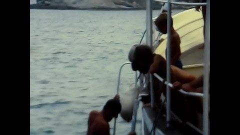 elba, italy july 14 1970:person on the boat descends from the ladder into the sea 70s sea
