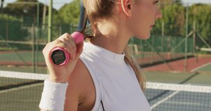 Video of caucasian female tennis player holding racket and looking at camera. professional tennis training, sport and competition concept.