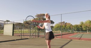 Video of happy caucasian female tennis player holding racket and serving. professional tennis training, sport and competition concept.