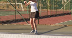 Video of happy caucasian female tennis player holding racket and hitting ball. professional tennis training, sport and competition concept.