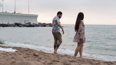Date at sea at dawn Lovers walk along the beach