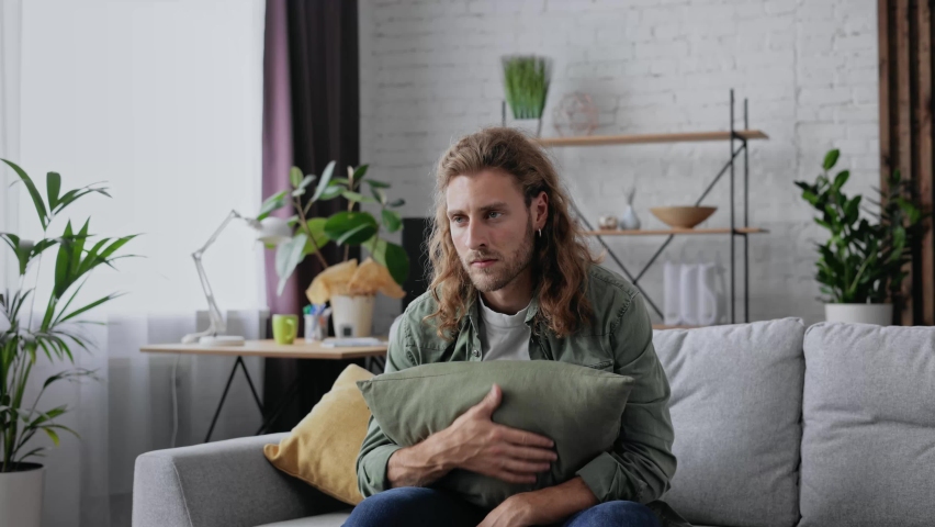 Exhausted overloaded young curly guy in casual shirt came home after work flopped down on sofa feels like squeezed lemon. Concept of after party, tired overworked person hard day, lack of energy | Shutterstock HD Video #1088141397