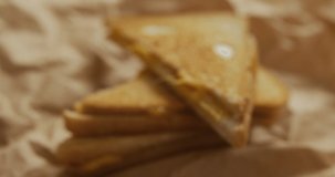 Video of close up of toasted cheese sandwiches on brown paper over grey background. fusion food and freshly made food concept.