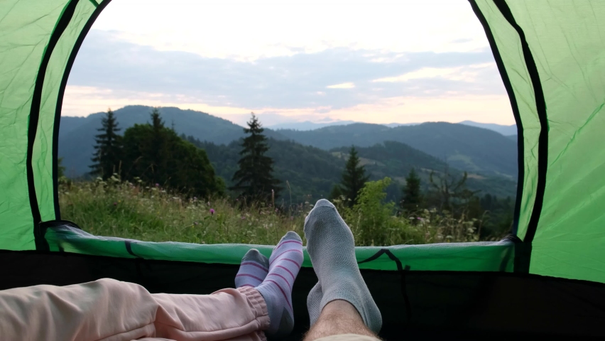 View of the legs of tourists resting in a tent, a couple in love climbed to the top of the mountain