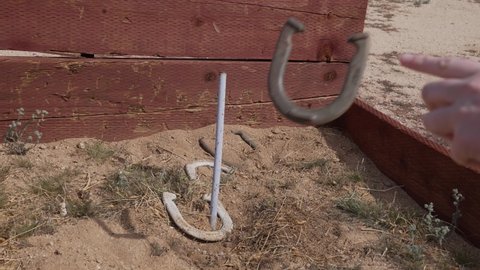 This POV video shows a horse shoe being thrown on to a stake in slow motion.