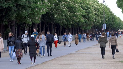 Paris, France - May 2019 : Tourists walking on the Champs-Elysees avenue by the Jardins des Champs-Élysées in Paris, France