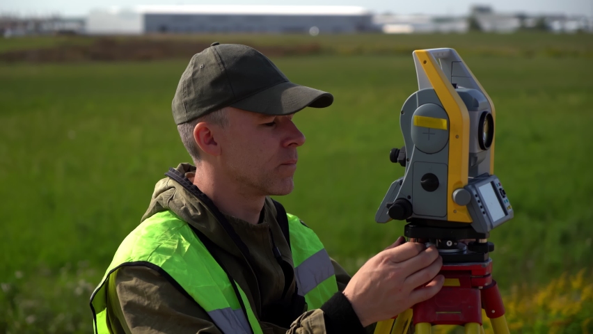 Close-up of a construction engineer setting up a total station on a tripod. Surveyor using digital level optical equipment.  Royalty-Free Stock Footage #1088148883