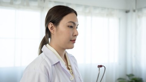4K 50fps, long-haired Asian female doctor stands inquiring about the patient's condition and talking with a serious face.	