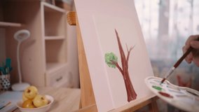 Girl paints picture of tree with paints on paper with brush at home. Close-up of picture. Slider shot. - Powered by Shutterstock - Get 15% off with code: PIKWIZARD15