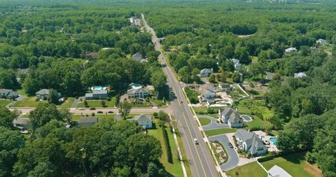 Flight a drone over a with low houses in Monroe town on a sunny day on between the forest landscape in New Jersey US