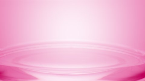 Macro shot of pink drop falls down on the surface of pink clear fluid creating concentric circles on pale pink background | Abstract skincare cosmetics mixing concept