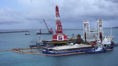 Okinawa.Japan 07.25.2019 
Floating crane platform with a huge bucket extracts sand from the bottom of the Pacific Ocean. Bottom deepening on sunny day