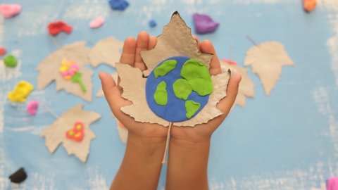 Child sculpturing plasticine planet for earth day. Protection of environment, Save our planet. Ecology concept. Concept of art learning and education