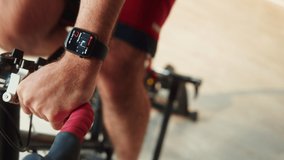 Sportsman riding bicycle, wearing fitness bracelet, home gym. Young man cycling, exercising in morning. Spanish guy preparing for competition, workout on stationary bike. Healthy lifestyle.  - Powered by Shutterstock - Get 15% off with code: PIKWIZARD15
