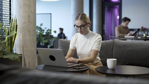 Young, beautiful and attractive business woman is finishing her daily work at modern co-working hub space and close the laptop down. She is completed with important project and ready for rest time