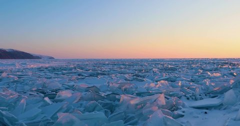 Beautiful winter landscape of frozen Lake Baikal at sunrise - Snowy ice hummocks with transparent blue piles of ice - BAikal Lake, Siberia